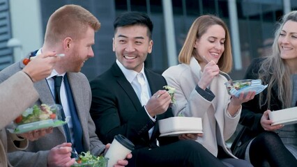 Group of international businesspeople eating lunch at city street outside of the office. - Powered by Adobe
