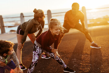 Family doing stretching exercises by the beach at sunset