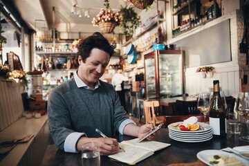 Smiling businessman doing finances in his restaurant