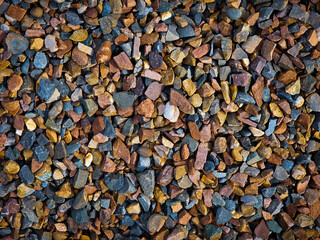 close-up of a gritty texture formed by a mixture of gravel and various stones.Smooth round pebbles texture background.
