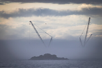 two port cranes in the fog at sunset