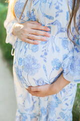 Closeup of a belly of a pregnant woman in a flower dress