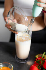 Chef girl mixing flour with eggs with a whisk for baking.