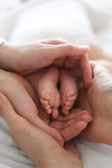 Mother and father hands holding newborn baby toes legs