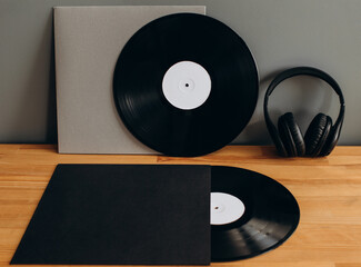Vinyl records with empty paper covers and headphones on the table. Mockup