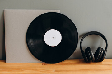 Vinyl record with paper envelope and headphones on gray background. Mockup