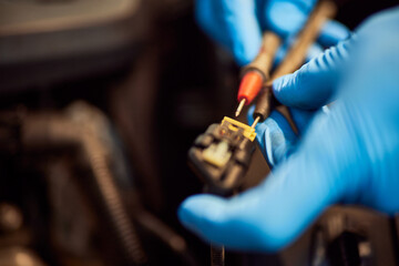 Hands of car mechanic working in auto repair service, wearing gloves.