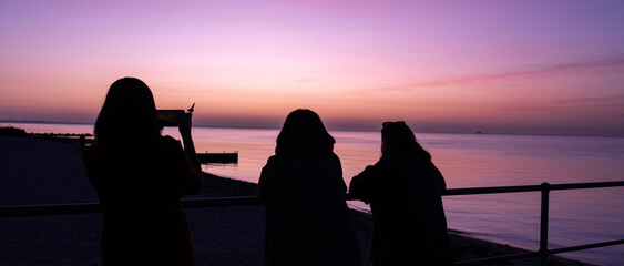 Silhouettes of women admiring the view of the sea at sunset