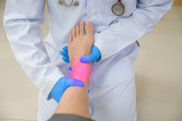 A doctor is examining the ankle of a woman who has an ankle injury. Foot treatment with an...