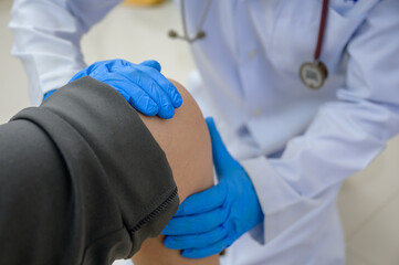 Doctor examining the knee of a woman who has a knee injury Knee joint treatment by an orthopedic...