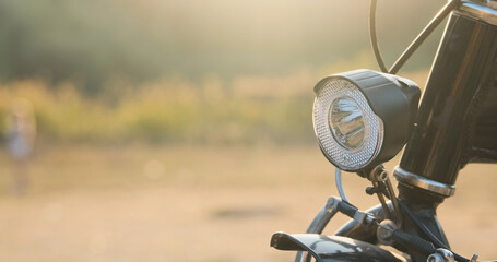 Bicycle front headlight, close-up, side view. Daytime, summer, folding bike frame