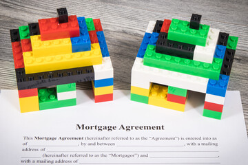 Houses made of toy blocks and mortgage agreement form. Method of financing building or purchase of...