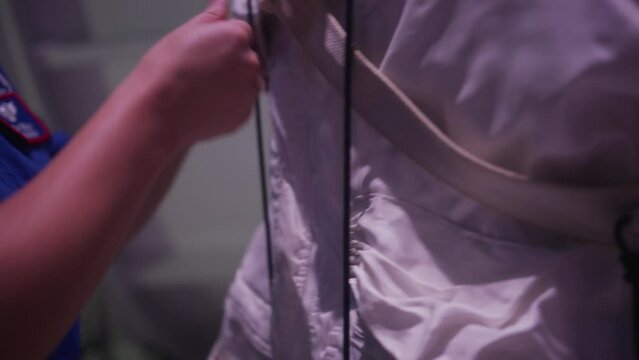 Astronaut having back straps adjusted - close up