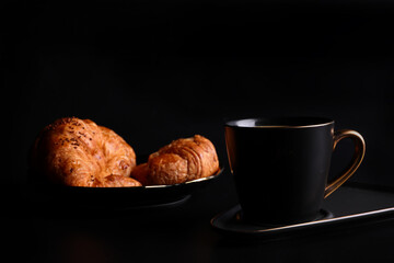 Hot latte coffee with Croissant coffee break isolated in black background