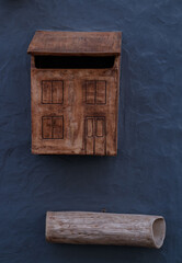 A bright retro looking green mailbox, or letterbox, affixed to the exterior wall of a blue house.