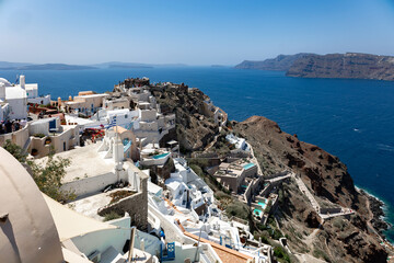 Santorini, Greece - 05 28 2023: Fira's caldera's view in the morning. Stacked white washed cave houses with infinity pools.  - obrazy, fototapety, plakaty
