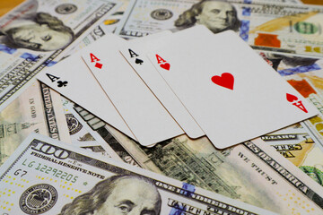 Four kind of ace cards over several one hundred dollar bills