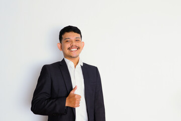 a young asian businessman stands and shows a gesture of pride and success