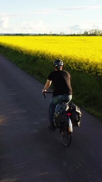 Man on a Bicycle Riding Past a Blooming Rapeseed Field
