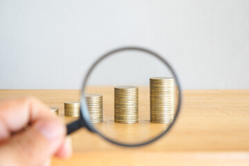 Magnifying Glass Examining Coins in Isolated White Background with Money, Currency, and Finance Concepts