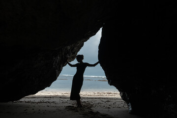 Outline of a girl posing against the backdrop of the ocean among the rocks