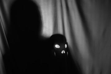 Silhouette of creepy ghost with skull behind grey cloth, space for text
