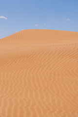 Fototapeta na wymiar Sand dunes with blue sky and a cloud in Morocco. High quality photo