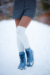 The girl has beautiful slender legs. Warm stockings, blue shoes. Snow all around