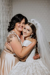 A beautiful and happy mother and her daughter, the bride, are standing next to each other. The best day for parents. Tender moments at the wedding.