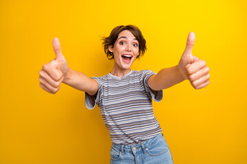 Photo of satisfied good mood funny woman dressed striped t-shirt two hands showing thumbs up to you isolated on yellow color background - obrazy, fototapety, plakaty