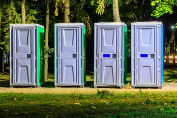 Cabins of public bio toilets at night in the park. Background with selective focus and copy space