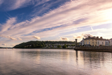 Fototapeta premium Sunset sky reflecting in a bay surrounded by a small seaside village. Menai Strain and Beaumaris North Wales