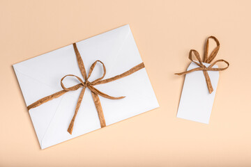 White envelope and blank label on a peach background. Congratulations concept for Easter, International Women's Day, Mother's Day and Birthday.