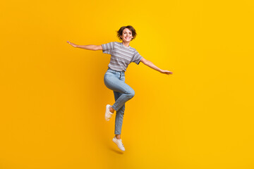 Full length photo of cheerful lovely person jumping arms wings flying empty space isolated on...
