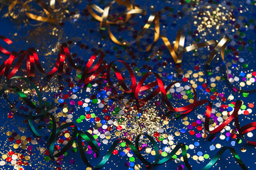 Multi-colored tinsel and confetti on a dark blue background. Festive, carnival background....