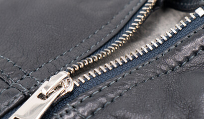 Macro shot of zipper on black leather texture background with stitching. Close-up of black leather...