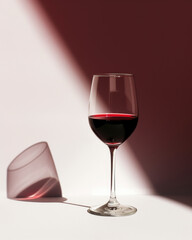 Einzelnes Rotweinglas im Spiel mit Licht und Schatten - obrazy, fototapety, plakaty