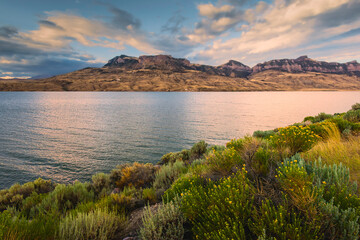 Water reservoir and river flanked by foothills and wild sagebrush. Cody, USA.