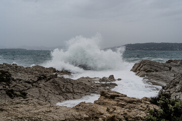 Waves crashing during storm on a rocky shore. High quality photo. Climate natural event weather