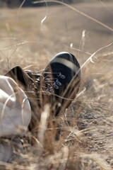 Close-up of leather hiking boots or ankle boots of a tourist sitting in dry grass. Concept - travel as a lifestyle.