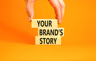 Branding and your brand story symbol. Concept words Your brands story on beautiful wooden blocks. Beautiful orange background. Businessman hand. Business branding your brand story concept. Copy space.