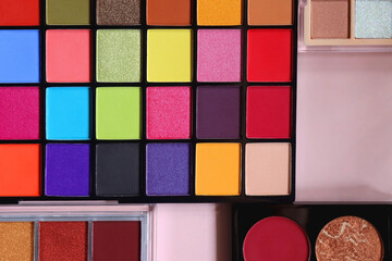 Various colorful eyeshadow palettes on bright pink background. Flat lay.