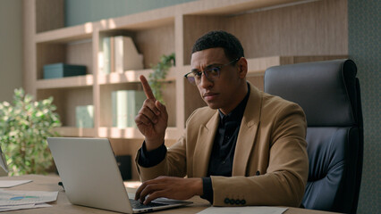 African American ethnic man serious businessman working online on laptop at office dissatisfied...