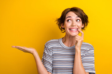 Photo of funny excited good mood woman dressed striped t-shirt look empty space palm show object isolated on yellow color background
