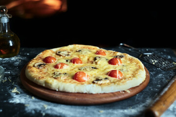 Pizza with mushrooms and tomatoes with cheese on the background of the oven.