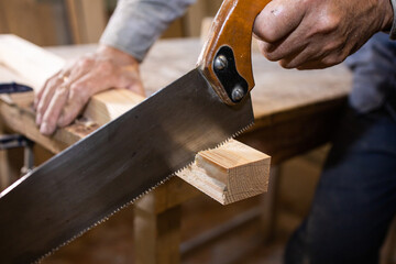 Carpenter in the workshop. Cutting wood with a saw