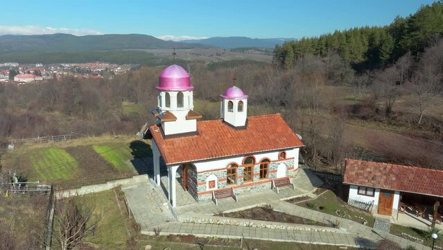 Aerial video where camera circles clockwise around St Cosmas and Damian chapel on the outskirts of Dobrinishte on a bright winter day.