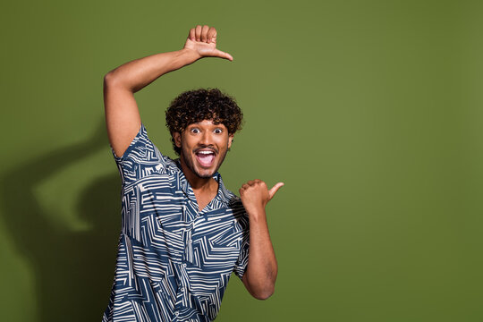 Portrait of young optimistic latin guy indicating forefingers empty space more benefits life in usa isolated on khaki color background