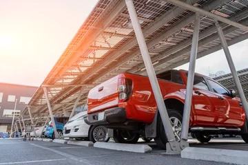 Fotobehang Car parking with canopy roof with solar panels. Solar power generation. Pickup car red with body © aapsky