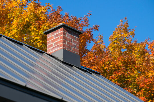 A red brick chimney in the Quebec fall colors